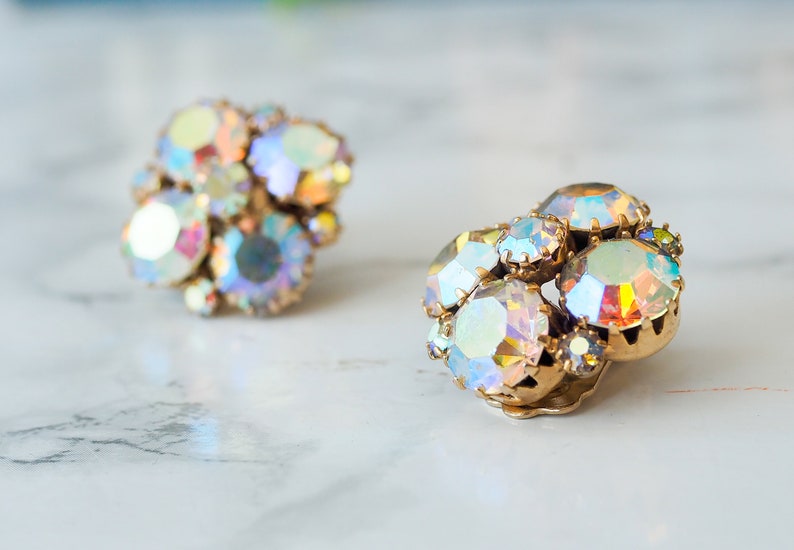 May include: A pair of iridescent gold tone clip-on earrings with a cluster of faceted rhinestones.