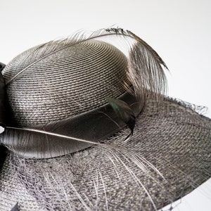 May include: A black straw hat with a large black bow and a long black feather.