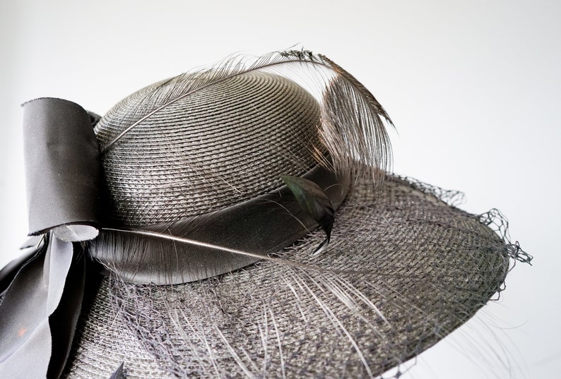 May include: A black straw hat with a large black bow and a long black feather.