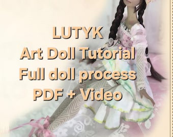 May include: A doll with long dark braids and blue eyes, wearing a pink and white dress with floral accents. The image includes text that reads "LUTYK Art Doll Tutorial Full doll process PDF + Video."