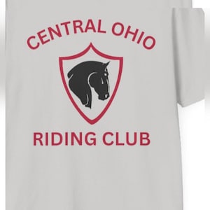 Peut inclure: Un t-shirt gris clair arborant un emblème en forme de bouclier rouge avec la silhouette d'une tête de cheval noire. Le texte "CENTRAL OHIO" est arqué au-dessus du bouclier et "RIDING CLUB" est imprimé en rouge en dessous. Logo sur la poitrine.