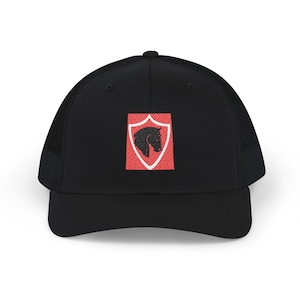 Peut inclure: Une casquette trucker noire avec un panneau avant structuré et un arrière en filet. Au centre se trouve un écusson brodé représentant un bouclier rouge à bordure blanche, orné d'une silhouette noire de tête de cheval tournée vers la droite.