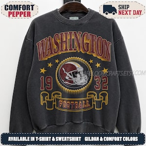 May include: A charcoal gray crewneck sweatshirt featuring a graphic print with the text WASHINGTON in large arched letters, the numbers 19 and 32 on the sides, and a football helmet in the center above a banner with the word FOOTBALL.