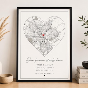 May include: A framed wall art print featuring a black and white street map shaped like a heart with a small red heart at the centre. The text reads: Our forever starts here, JAMES & AMELIA, 51.5074° N, 0.1278° W, 30TH AUGUST 2024, YOU ARE MY ALWAYS.