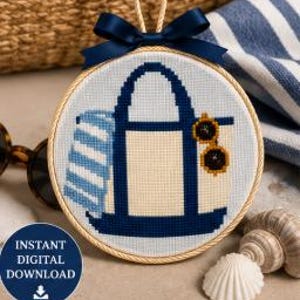May include: A circular embroidery hoop containing a cross-stitch pattern of a navy blue and cream tote bag with a striped towel and yellow sunglasses. A navy blue ribbon is tied at the top, and the text Instant Digital Download is visible.
