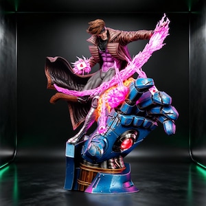 Può includere: Una statuetta da collezione di un personaggio con capelli castani, che indossa un trench marrone e una maglia viola, in piedi su una grande mano robotica blu. Il personaggio tiene carte energetiche rosa luminose con effetti.