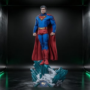 May include: A detailed Superman figurine standing on a jagged, crystalline base. The figure wears a textured blue suit with a red cape, a yellow belt, and a prominent red and yellow S-shield emblem on the chest. The base features blue crystals.