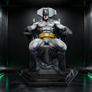 May include: A detailed gray and black Batman figurine seated on a high-backed throne. The character wears a dark cowl, a cape, and a bright yellow utility belt with rectangular pouches. The figure is positioned on a dark, geometric base.
