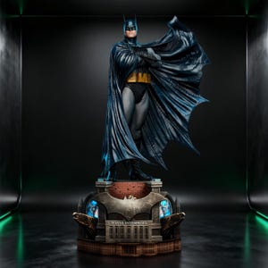 May include: A detailed Batman statue featuring a dark blue and black suit with a yellow utility belt and a flowing cape. The figure stands on a base designed like a building facade with the text Wayne Enterprises clearly visible on the front.