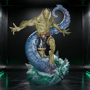 May include: A detailed figurine of a muscular, green-skinned humanoid creature with gills and a wide grin. The figure wears black shorts with a brown belt and is surrounded by a large, blue, textured tentacle rising from a base of swirling green water.