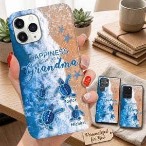 May include: A phone case featuring a beach scene with blue ocean waves, tan sand, and four blue sea turtles. The text reads "HAPPINESS IS BEING A Grandma" with the names "Liam," "Taylor," "Ben," and "Michael" printed near each turtle.