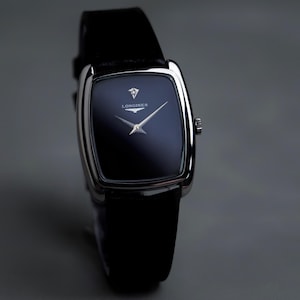 May include: A Longines wristwatch featuring a polished silver-tone cushion-shaped case and a deep black dial. The dial displays the Longines logo and text in white, with two slender silver hands. It is attached to a smooth black leather strap.