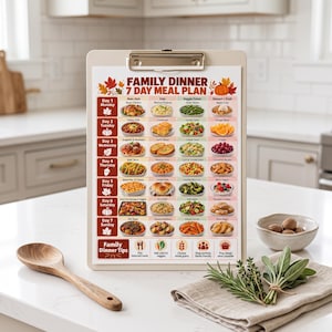 May include: A clipboard holding a printed 7-day family dinner meal plan with a fall-themed design. The chart features a grid layout with daily food images, text labels for each meal, and a section at the bottom titled Family Dinner Tips with icons.