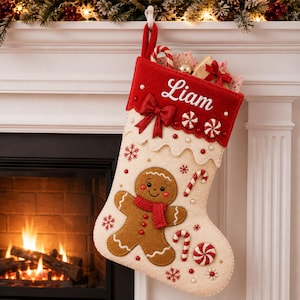 May include: A cream-colored felt Christmas stocking featuring a red cuff embroidered with the name Liam. The stocking is decorated with a brown gingerbread man, red and white candy canes, peppermint swirls, and red snowflake accents.