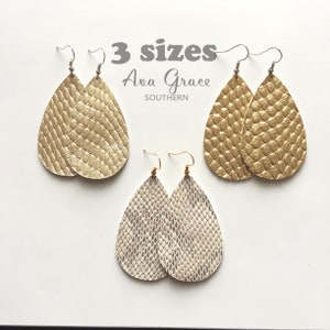 May include: Three pairs of teardrop-shaped leather earrings in gold and white with a snakeskin pattern. The earrings are available in three sizes.