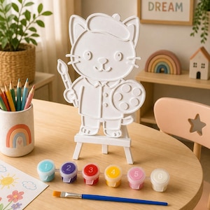 May include: A white, three-dimensional cat figure wearing a beret, holding a paintbrush and a paint palette, displayed on a small wooden easel. Included are six numbered paint pots in blue, purple, red, yellow, pink, and white, plus a brush.