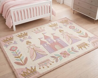Puede incluir: Una alfombra rectangular con fondo color crema y un motivo central de castillo en rosa y morado. El diseño incluye ilustraciones de dos figuras con vestidos, varias coronas doradas y tallos florales en tonos rosa y azul claro.