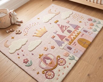 Puede incluir: Una alfombra rectangular de color rosa suave con un diseño de mechones que representa un castillo, un carruaje, una corona, nubes, estrellas y flores en tonos pastel crema, lavanda, melocotón y oro. La alfombra tiene una superficie texturizada.