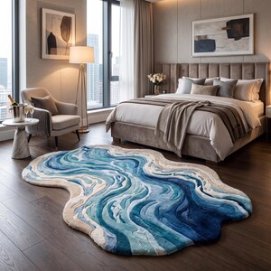 Puede incluir: Una alfombra de forma org&aacute;nica irregular con un patr&oacute;n fluido y superpuesto de colores azul marino profundo, azul real, azul claro y crema. La alfombra tiene una superficie texturizada y afelpada que imita el aspecto del agua.