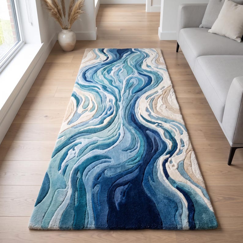 Puede incluir: Una alfombra rectangular con un dise&ntilde;o abstracto y texturizado de l&iacute;neas org&aacute;nicas fluidas en tonos azul marino profundo, turquesa brillante, azul cielo claro y beige crema, creando un patr&oacute;n en capas que recuerda a las olas.
