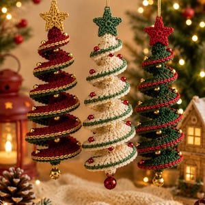 May include: Three spiral-shaped Christmas tree ornaments made of crocheted yarn. One is deep red with a gold star, one is cream with a green star, and one is dark green with a red star. Each features small metallic beads and a hanging bell.