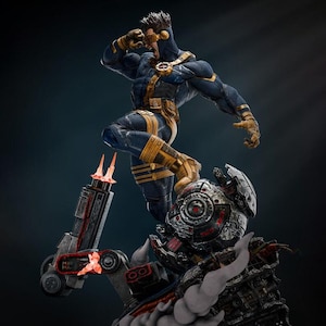 May include: A detailed collectible statue of a muscular figure in a dark blue and yellow tactical suit with a visor, standing atop a damaged, metallic robotic head with glowing red accents and mechanical components emitting smoke and light.
