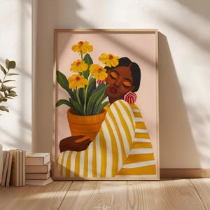 Può includere: Una stampa artistica incorniciata raffigurante una persona dalla pelle scura e lentiggini che indossa una camicia a righe gialle e bianche, mentre tiene un vaso di terracotta pieno di fiori gialli. La persona ha gli occhi chiusi e indossa orecchini a righe rosse e bianche.