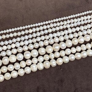 May include: Multiple strands of white freshwater pearls arranged in a gradient pattern. The strands feature small, uniform round pearls at the top, transitioning to larger, irregularly shaped, baroque-style pearls at the bottom, all showing a lustrous finish.