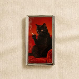 Könnte beinhalten: Ein rechteckiges Zigarettenetui aus silberfarbenem Metall mit einem aufgedruckten Bild einer schwarzen Katze, die auf einer roten Fläche sitzt und eine brennende Zigarette hält, wobei Rauch vor einem einfarbig roten Hintergrund aufsteigt.