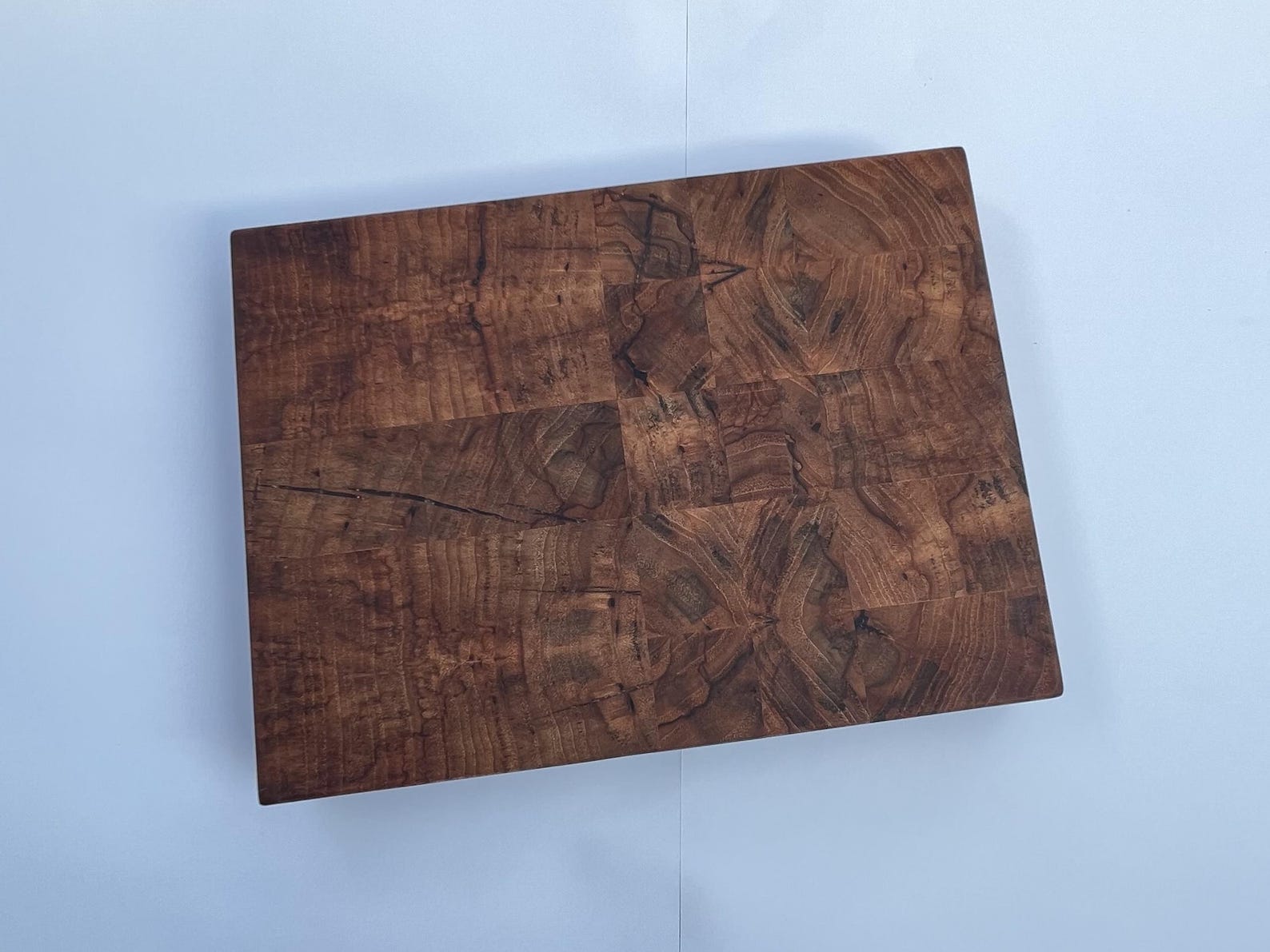 Small pecan end-grain cutting board viewed from above, showing dark brown grain and natural figure