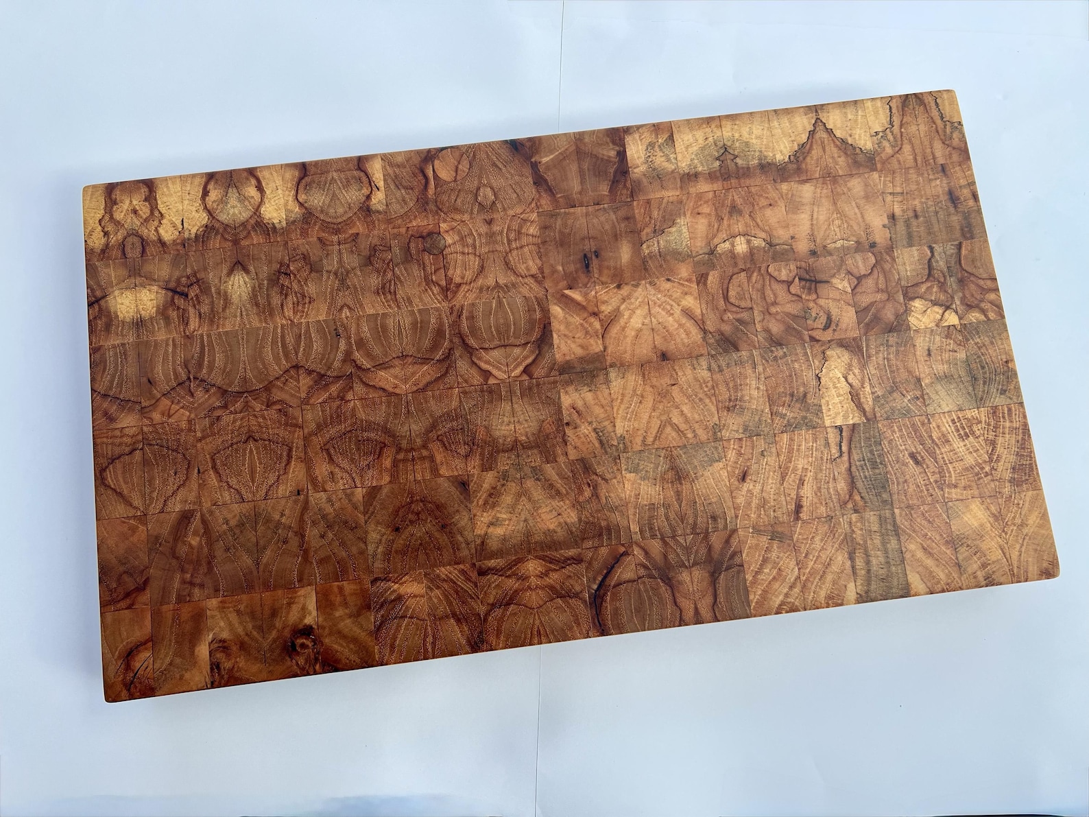 Large rectangular pecan end-grain cutting board with golden and dark brown swirling figure