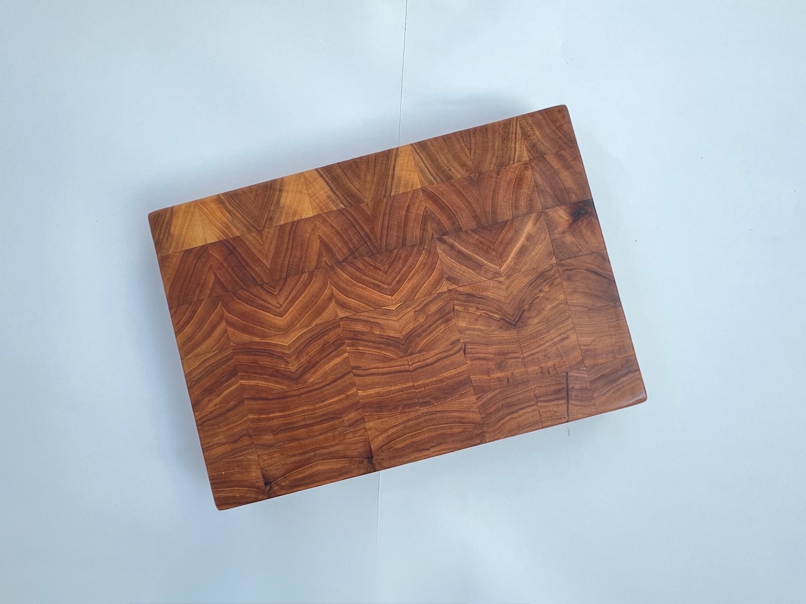 Elm end-grain cutting board viewed from above, with warm brown bookmatched grain