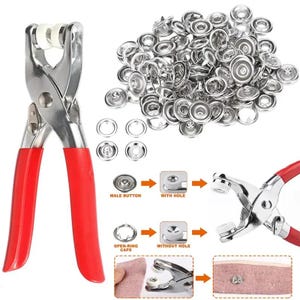 Peut inclure: Un outil de pose de boutons-pression en métal avec des poignées en caoutchouc rouge vif et des inserts en plastique blanc. L'ensemble comprend un grand tas de composants métalliques argentés, incluant des boutons mâles, femelles et des anneaux.
