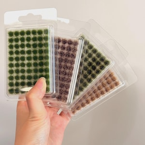 Può includere: Quattro confezioni blister in plastica trasparente contenenti ciuffi d'erba statica in miniatura in varie tonalità di verde e marrone. Ogni confezione presenta una griglia di piccoli gruppi di fibre testurizzate per modellismo.