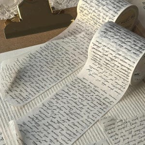 Pode incluir: Um rolo de fita washi semitransparente com um padrão repetitivo de escrita cursiva preta que imita cartas antigas escritas à mão. A fita está parcialmente desenrolada, exibindo o texto detalhado em estilo latino na sua superfície.