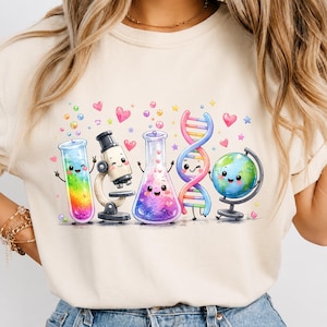 May include: A cream-colored crewneck sweatshirt featuring a colorful graphic print of five anthropomorphic science items: a rainbow-filled test tube, a microscope, a purple flask, a DNA double helix, and a globe, all surrounded by small hearts and stars.