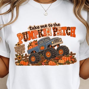 Puede incluir: Una camiseta blanca con un gráfico de un camión monstruo azul que transporta calabazas. El texto dice "take me to the PUMPKIN PATCH" y "PUMPKINS FARM FRESH FUN" en un letrero de madera. El diseño incluye patrones de cuadros y girasoles.
