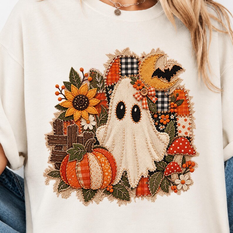 Peut inclure: Un t-shirt couleur cr&egrave;me arborant un motif central compos&eacute; d'un fant&ocirc;me blanc, d'une citrouille, d'un tournesol, d'un croissant de lune, d'une chauve-souris et de champignons rouges. Le design inclut des textures patchwork et des boutons.