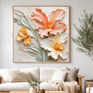 May include: A square wall art piece featuring a textured impasto oil painting of three large, blooming flowers in shades of peach, soft orange, and cream. The petals have visible, thick brushstrokes, and the stems and leaves are painted in muted sage green against a neutral, off-white background.