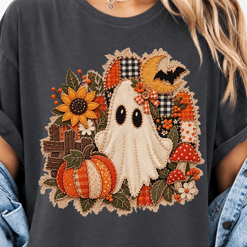 Peut inclure: Un t-shirt gris anthracite avec un motif central repr&eacute;sentant un fant&ocirc;me blanc entour&eacute; d'un design en patchwork compos&eacute; d'une citrouille, d'un tournesol, de champignons rouges, d'un croissant de lune jaune, d'une chauve-souris et d'une cl&ocirc;ture.