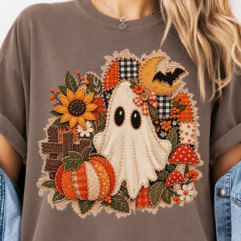Peut inclure: Un t-shirt gris anthracite avec un motif central repr&eacute;sentant un fant&ocirc;me blanc, une citrouille, un tournesol, des champignons rouges et un croissant de lune. Le design int&egrave;gre des motifs patchwork, des tissus &agrave; carreaux et des d&eacute;tails cousus.