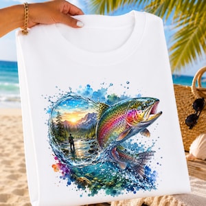 Peut inclure: Un t-shirt blanc orné d'un motif aquarelle coloré représentant une truite arc-en-ciel sautant hors de l'eau. Le design inclut un paysage avec des montagnes, une forêt, un coucher de soleil et une personne pêchant dans une rivière, entouré d'éclaboussures.