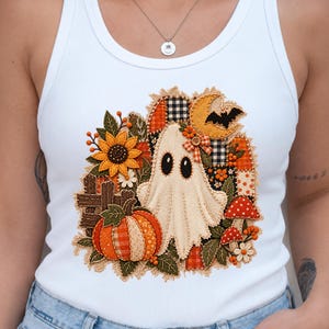 Peut inclure: Un d&eacute;bardeur blanc c&ocirc;tel&eacute; orn&eacute; d'un &eacute;cusson brod&eacute; central repr&eacute;sentant un fant&ocirc;me, une citrouille, un tournesol, des champignons et un croissant de lune. Le motif int&egrave;gre diverses textures de tissu, dont des carreaux orange et noirs.