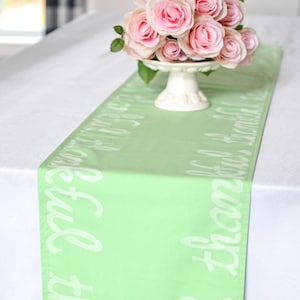 Pode incluir: Um corredor de mesa verde claro com letras brancas que dizem "Sejamos gratos" e "Feliz outono a todos". Um buquê de rosas cor-de-rosa está em um pedestal branco no fundo.