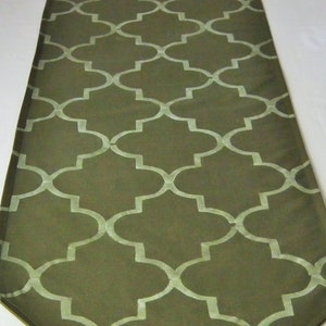 Pode incluir: Um corredor de mesa verde com um padrão geométrico branco. O padrão é um desenho repetitivo de quadrifólios.