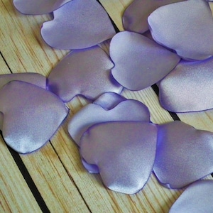 May include: A scattering of lavender satin heart-shaped petals. These petals are perfect for adding a touch of elegance to weddings, parties, or other special events.