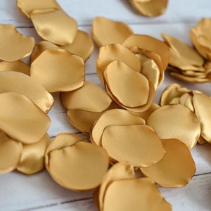 May include: A pile of gold satin rose petals. The petals are soft and silky, and they would be perfect for a wedding or other special occasion.