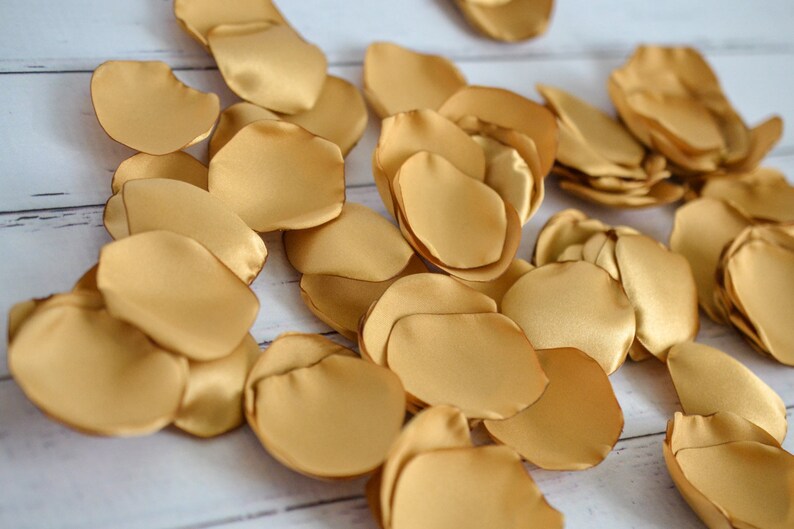 May include: A pile of gold satin rose petals. The petals are soft and silky, and they would be perfect for a wedding or other special occasion.
