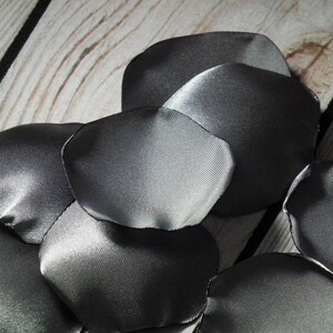 May include: A collection of grey satin rose petals, ideal for wedding decorations or crafting projects.