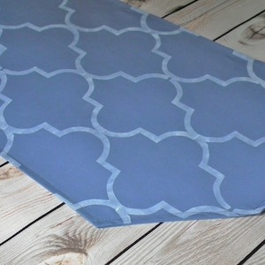 May include: A blue table runner with a white geometric pattern. The runner has a pointed end and is made of fabric.